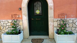 Une porte verte avec une pancarte indiquant «Bienvenue», le numéro 35, et deux jardinières de chaque côté.