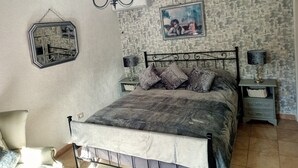 Une chambre à coucher avec un lit, un lustre, un miroir, un tableau au mur et un papier peint à motifs.