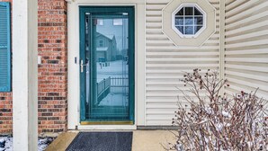 Una casa con una porta verde, un muro in mattoni e una finestra con cornice esagonale.