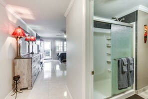 A hallway with a vanity, red lamps, and a shower area with a glass door. - North Myrtle Beach Studio w/ Pool: Walk to Shore! (North Myrtle Beach)