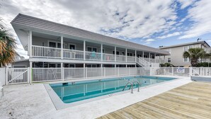 Un bâtiment à deux étages doté d’une piscine et d’une terrasse en bois.