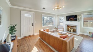 A living room with a wooden sofa, a fireplace, and a television. - Lovely Tulsa Vacation Rental ~ 3 Mi to Downtown! (Tulsa)