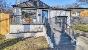 A two-story house with a front porch, a garage, and a staircase leading to the entrance. - Lovely Tulsa Vacation Rental ~ 3 Mi to Downtown! (Tulsa)