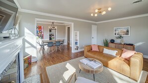A spacious living room with a leather sofa, a coffee table, and a fireplace. There is a dining area with a table and chairs in the background. - Lovely Tulsa Vacation Rental ~ 3 Mi to Downtown! (Tulsa)