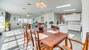A spacious kitchen with white cabinets, a dining area with a wooden table and chairs, and a bright ceiling light fixture.