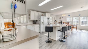 A modern kitchen with white cabinets, a central island with bar stools, and a hanging key rack.