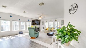 A spacious living room with a ceiling fan, a television, and a large potted plant.