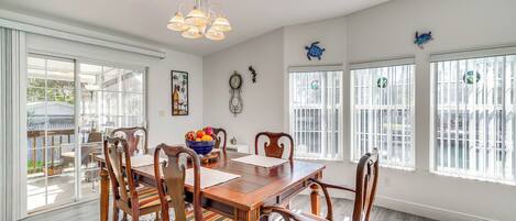 A dining room with a wooden table, chairs, and a chandelier.