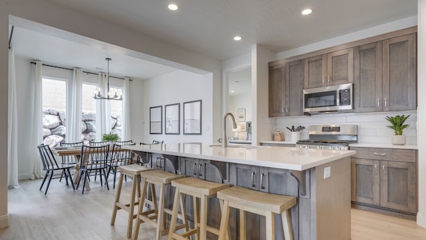 Cozinha moderna com uma ilha grande, banquetas, armários de madeira e micro-ondas embutido.