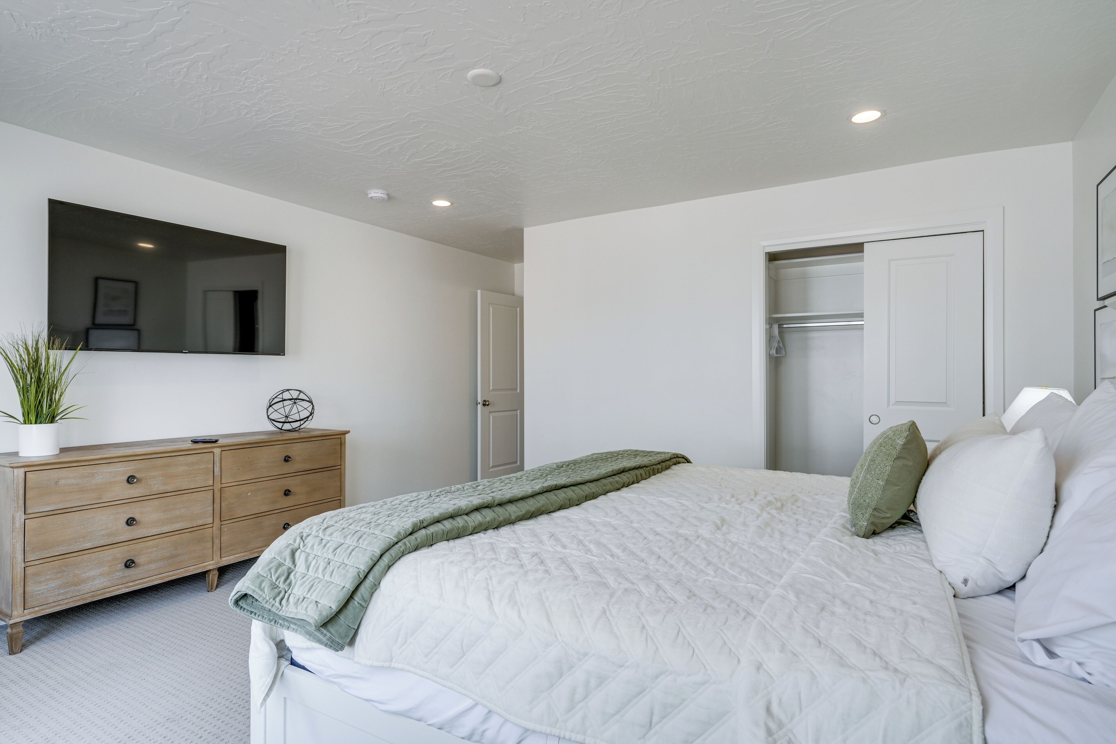 Un dormitorio con cama, cómoda, espejo y armario.