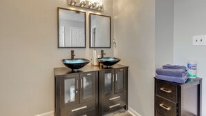 Une salle de bain avec deux lavabos, un miroir et un meuble contenant des serviettes et des produits de nettoyage.