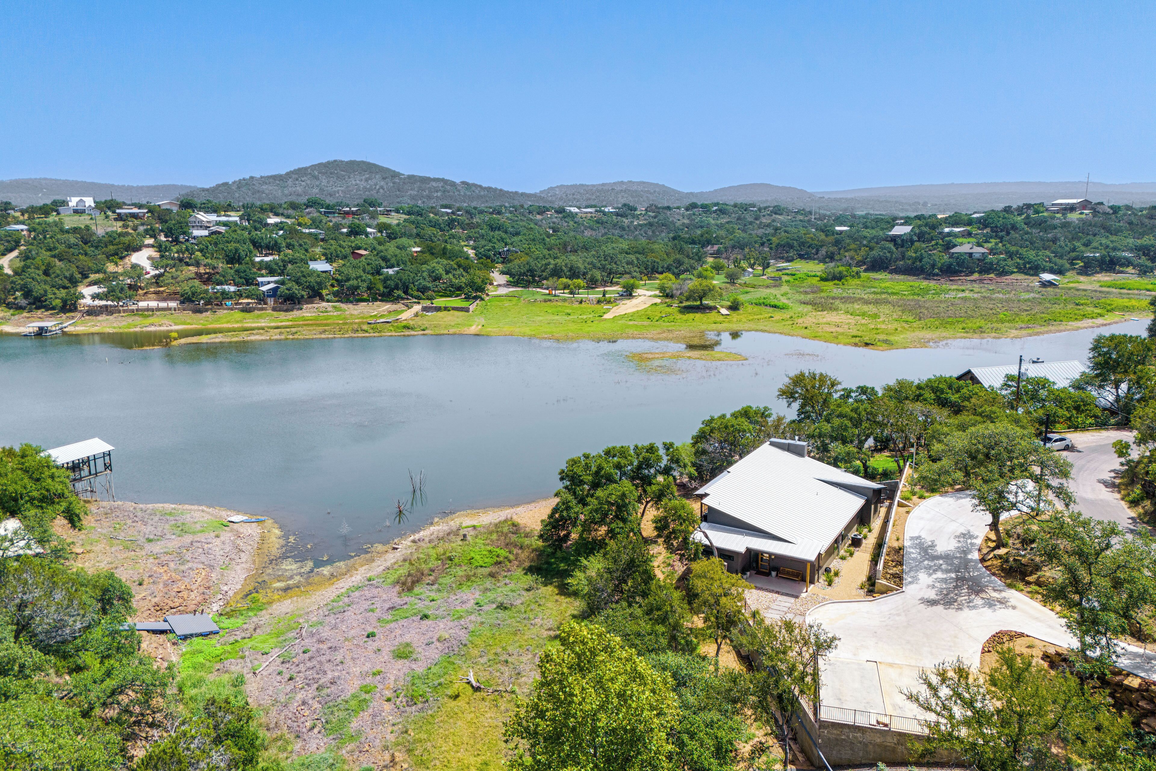 A lakeside property with a house, a boat dock, and surrounding greenery.