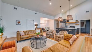 A modern living room with a sofa, armchairs, a coffee table, and a kitchen in the background.