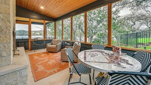 A covered outdoor seating area with a table, chairs, and a rug.