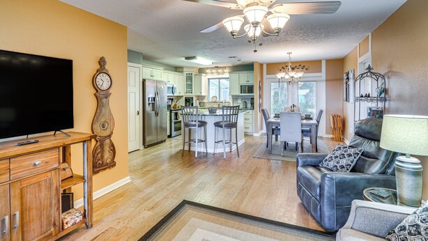 A spacious living room with a television, a wooden cabinet, a leather sofa, and a ceiling fan. - Auburndale Vacation Rental w/ Yard & Lake Views (Auburndale)
