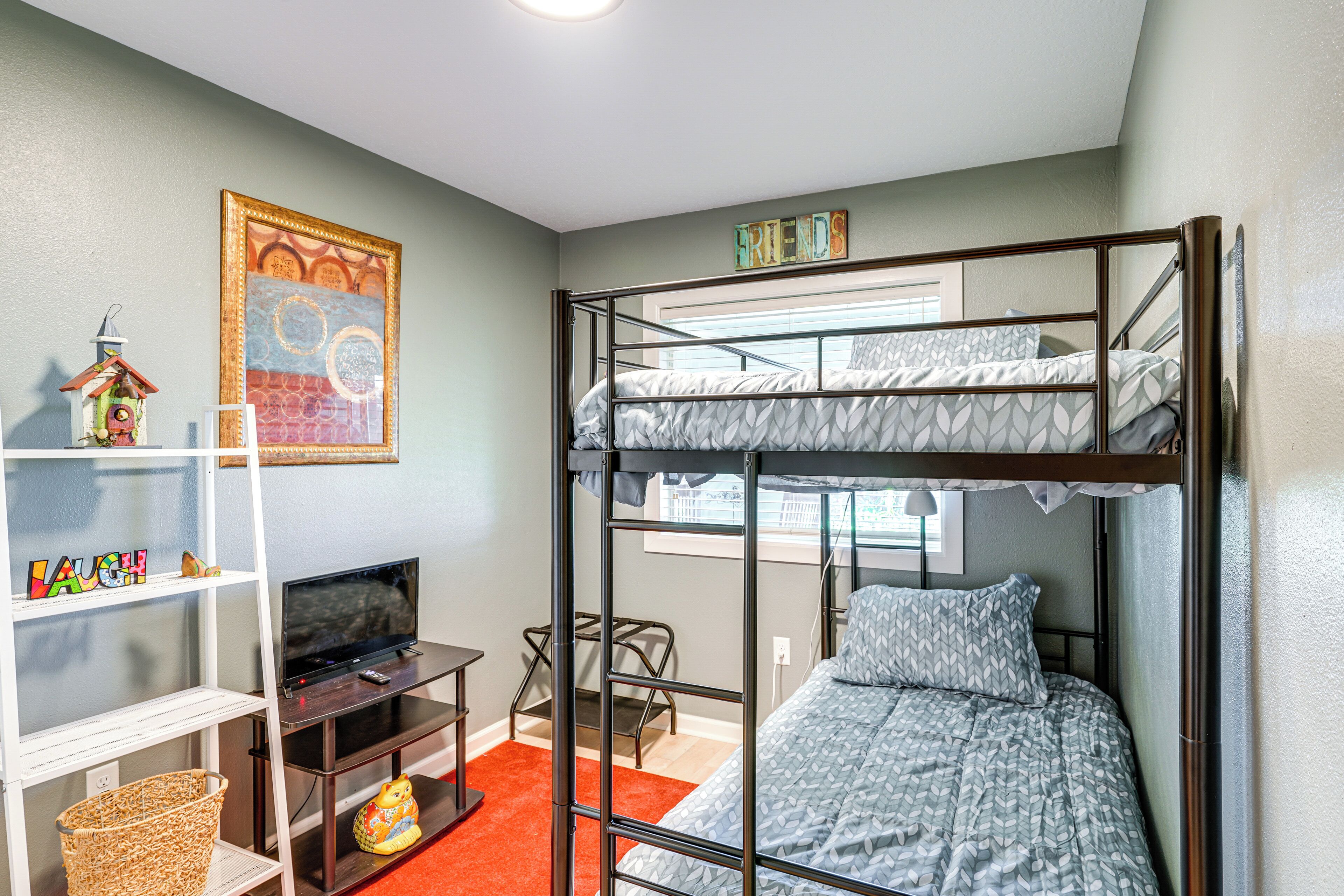 A bunk bed room with a television, bookshelf, and a painting on the wall.