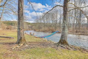 A hammock between trees by a river. - Mcdowell Highland County River Retreat w/ Views! (McDowell)