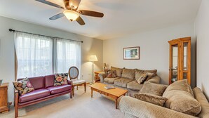A living room with a red sofa, beige sofa, wooden coffee table, and a ceiling fan. - Mcdowell Highland County River Retreat w/ Views! (McDowell)