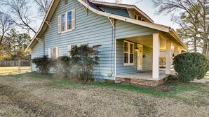 A single-story house with a porch, a fenced yard, and a small garden area. - Charming Starkville Rental ~ 2 Mi to Msu! (Starkville)