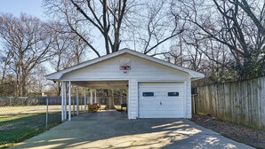 A white garage with a covered entryway, a wooden fence, and leafless trees in the background. - Charming Starkville Rental ~ 2 Mi to Msu! (Starkville)
