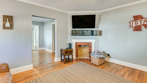A living room with a fireplace, a television mounted above it, and a wall-mounted sign. - Charming Starkville Rental ~ 2 Mi to Msu! (Starkville)