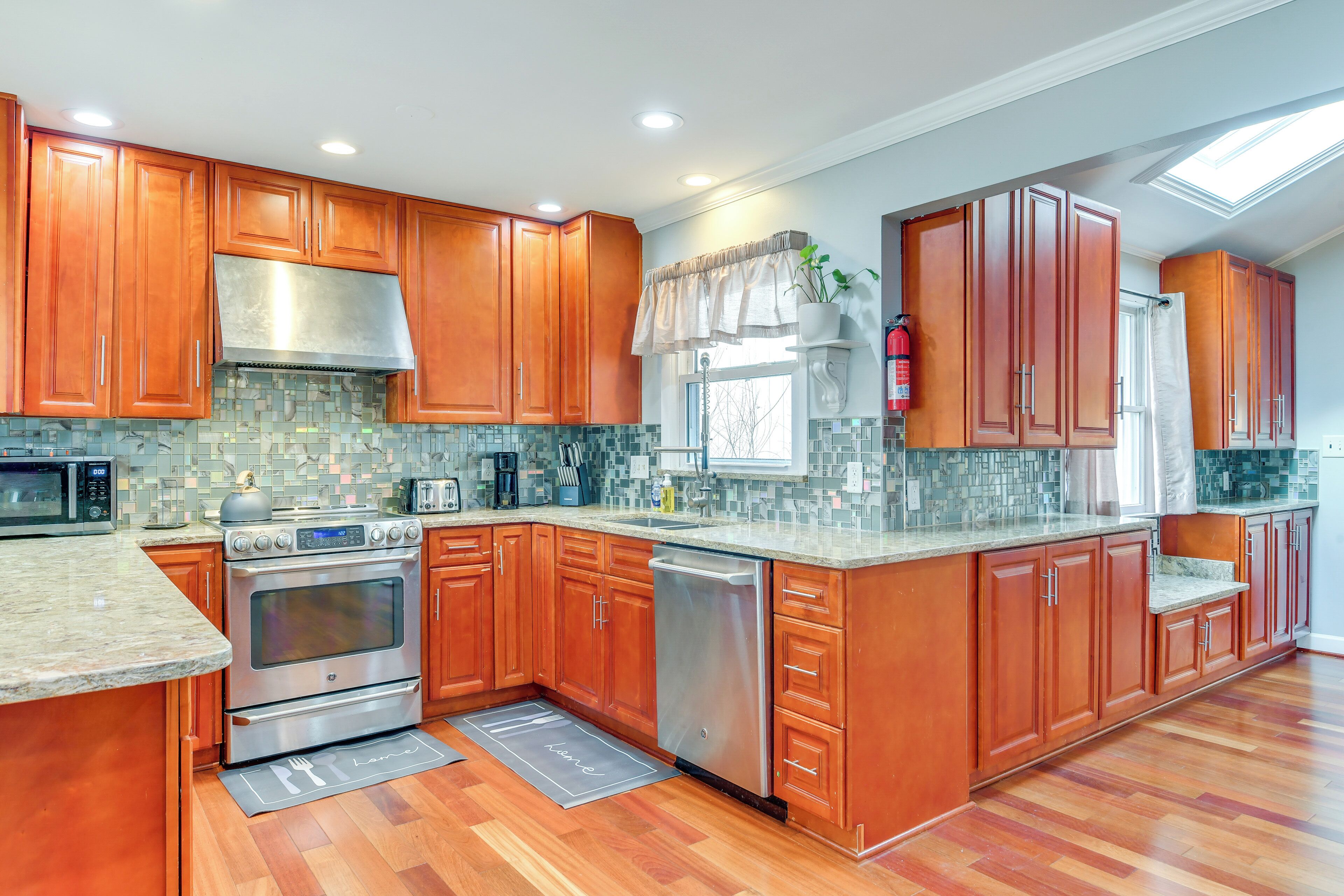 A modern kitchen with wooden cabinets, stainless steel appliances, and a tiled backsplash.
