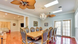 A spacious dining room with a large wooden table and ornate chairs, a chandelier, and ceiling fans. - Spacious Home w/ Tranquil Patio ~ 29 Mi to DC! (Severn)