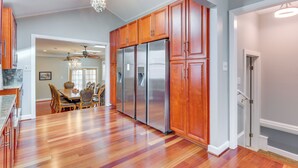 A spacious kitchen with wooden cabinets, stainless steel appliances, and a dining area with a chandelier. - Spacious Home w/ Tranquil Patio ~ 29 Mi to DC! (Severn)