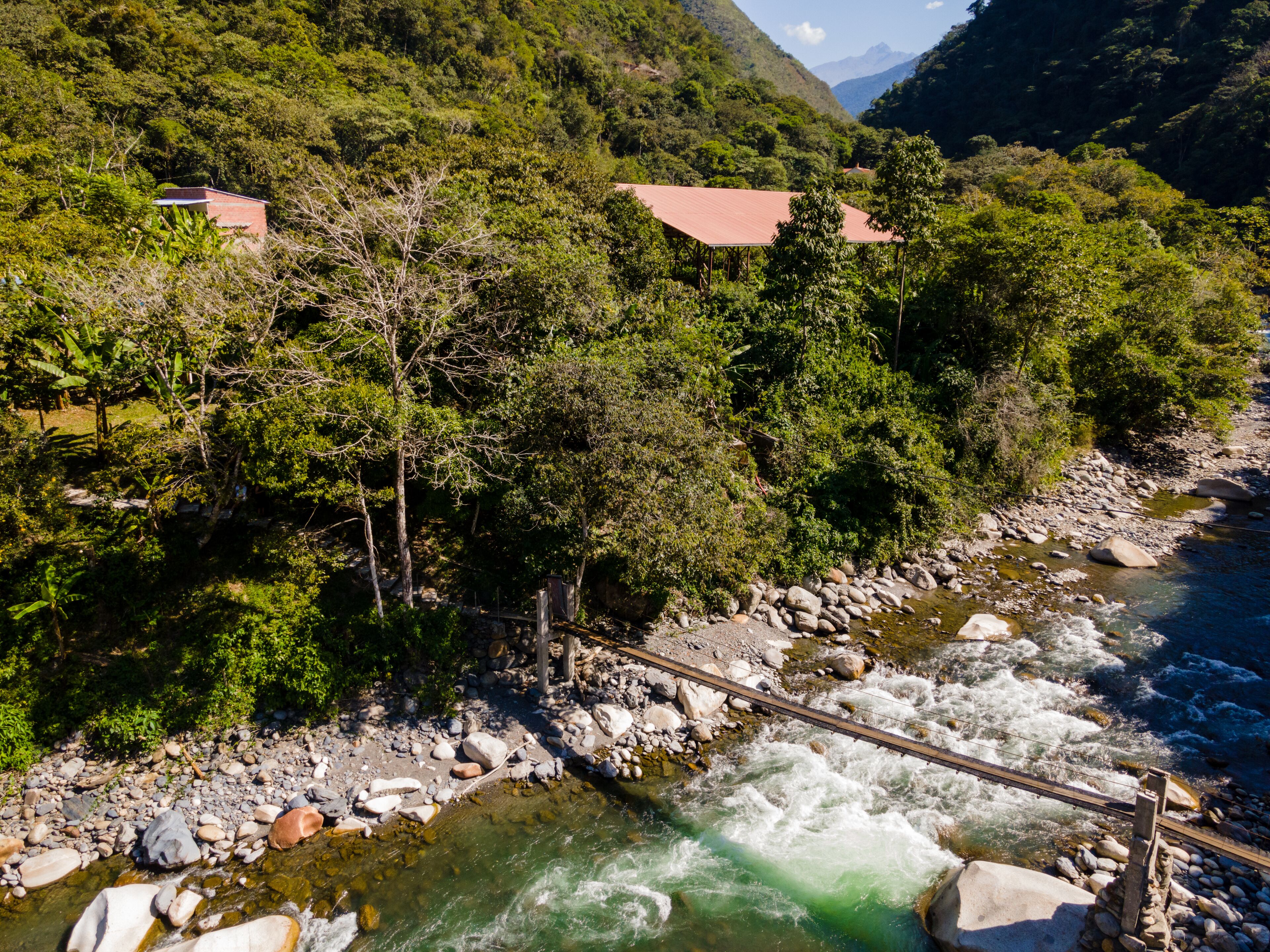 A river with a bridge, surrounded by lush greenery and hills.