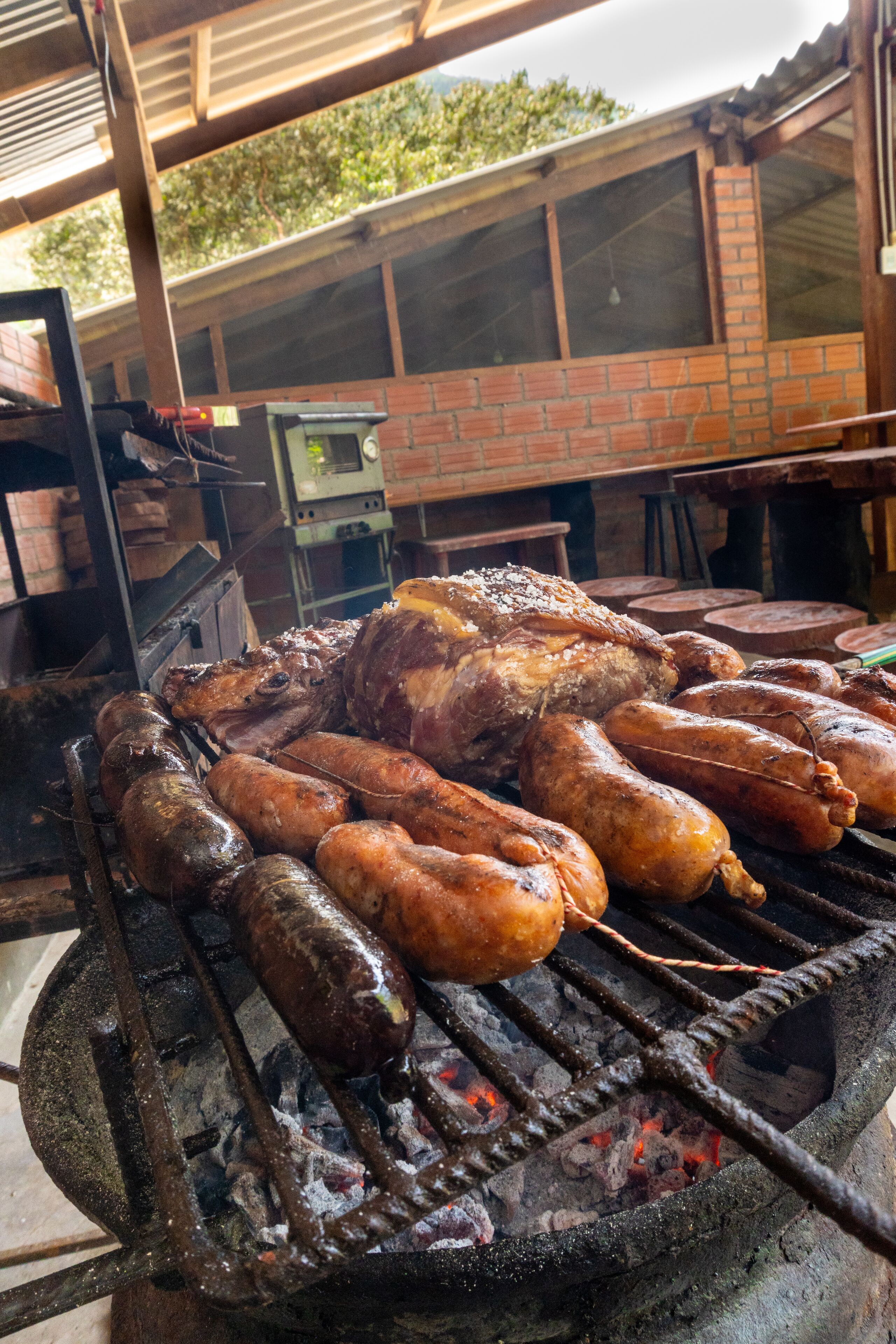Uma churrasqueira grande com vários tipos de carne assando ao ar livre.