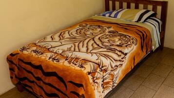 Een bed met een tijgerprint dekbedovertrek, een houten hoofdbord en een betegelde vloer.