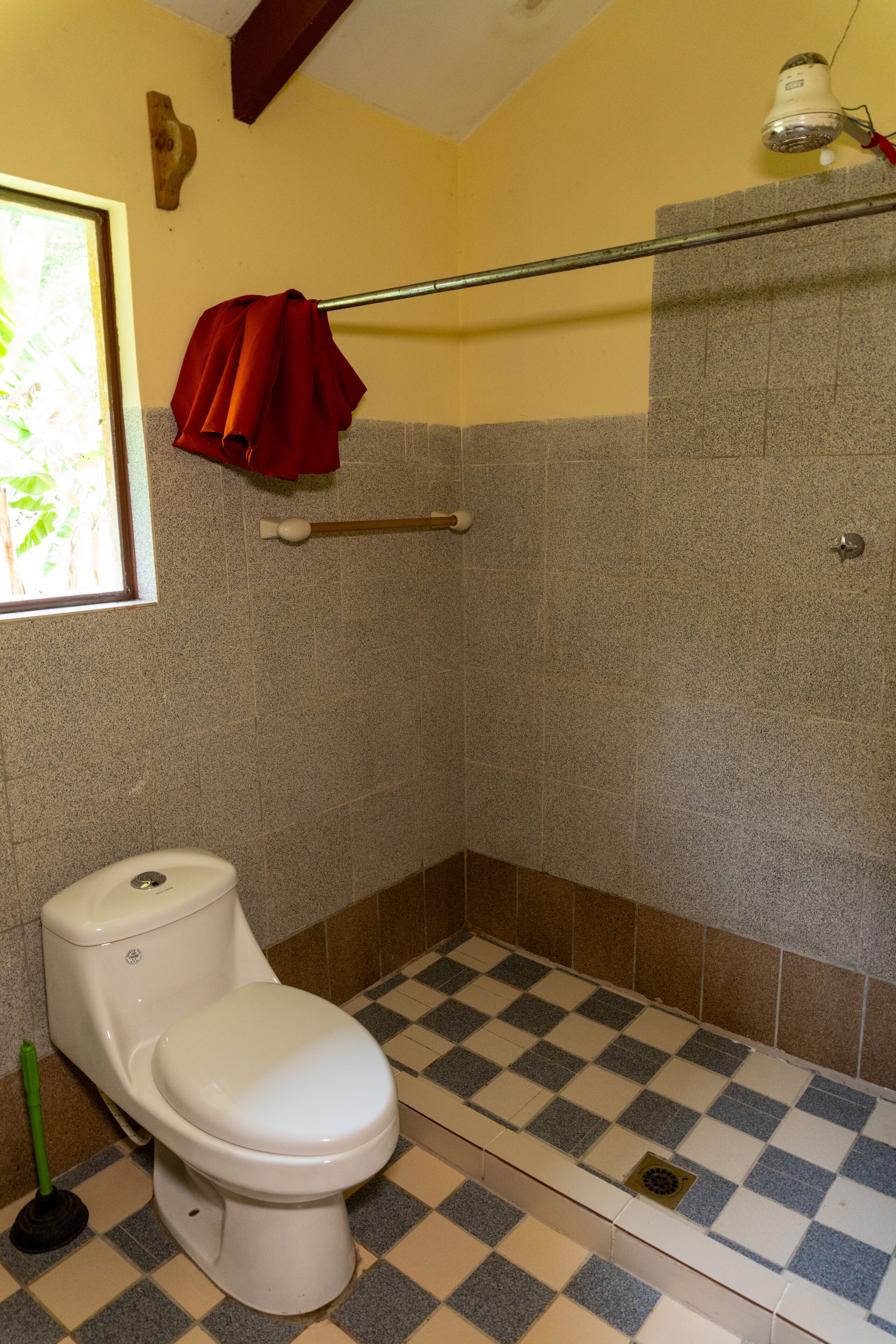 Une salle de bain avec des toilettes blanches, un carrelage à motifs et un espace douche.