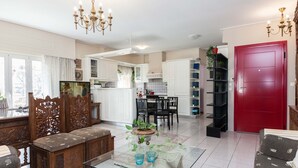 A spacious living room with a glass coffee table, wooden furniture, and a red door. - Classical Beauty 3Bd Apt in Nea Filothei (Athens)