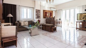 A spacious living room with a sofa, a glass coffee table, a wooden cabinet, and a television. - Classical Beauty 3Bd Apt in Nea Filothei (Athens)
