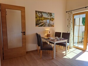 Un comedor con una mesa, sillas, una lámpara y un cuadro de un paisaje.