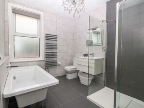 Un baño moderno con lavamanos, inodoro y zona de ducha blancos.
