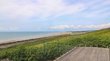 A wooden boardwalk with a view of a beach and ocean.