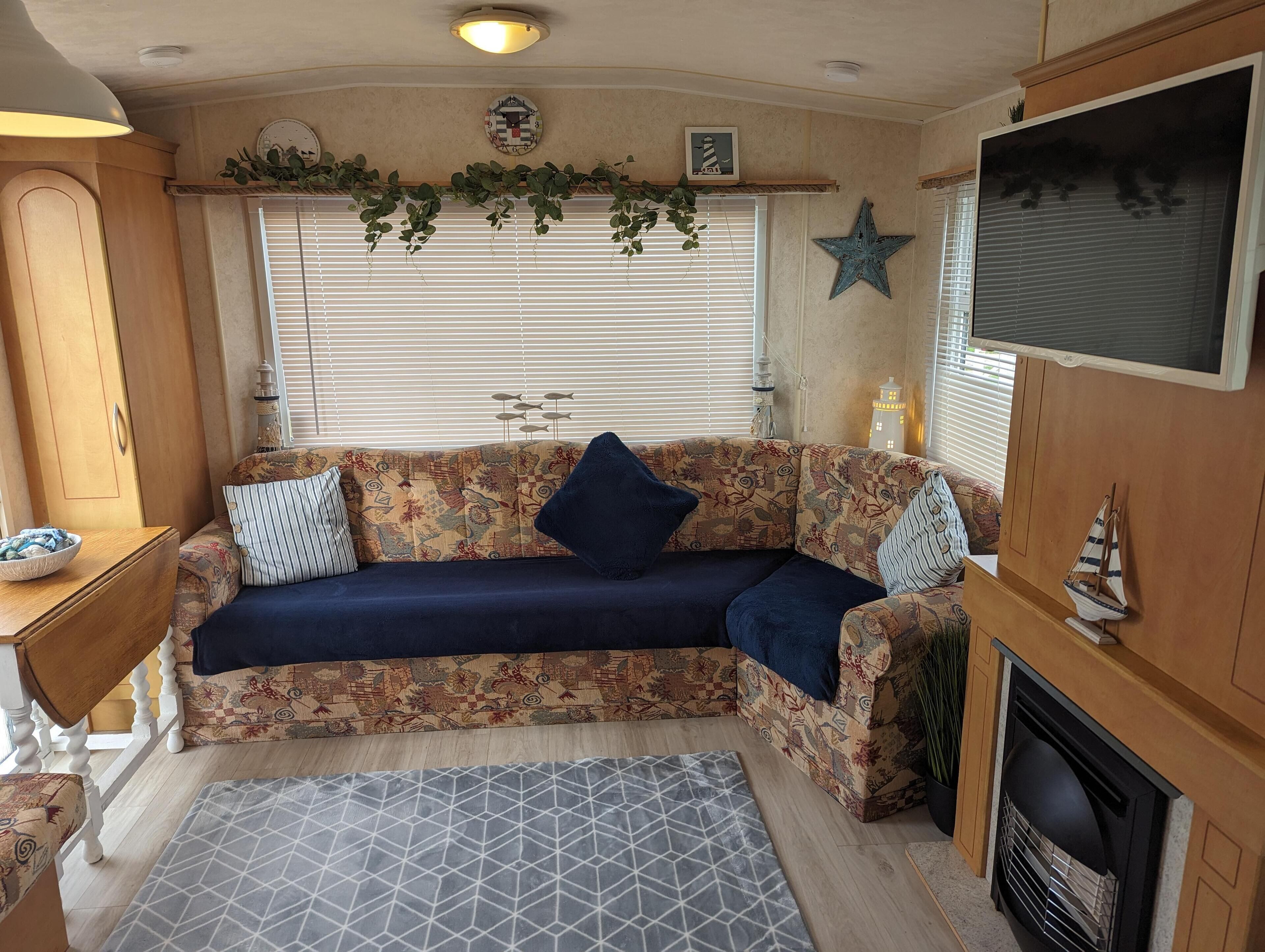 A cozy RV interior with a sofa, a television, a fireplace, and a decorative star on the wall.