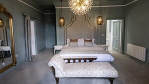 A bedroom with a large bed, a decorative mirror, and a chandelier. - Welbeck Manor and Golf  (Plymouth)