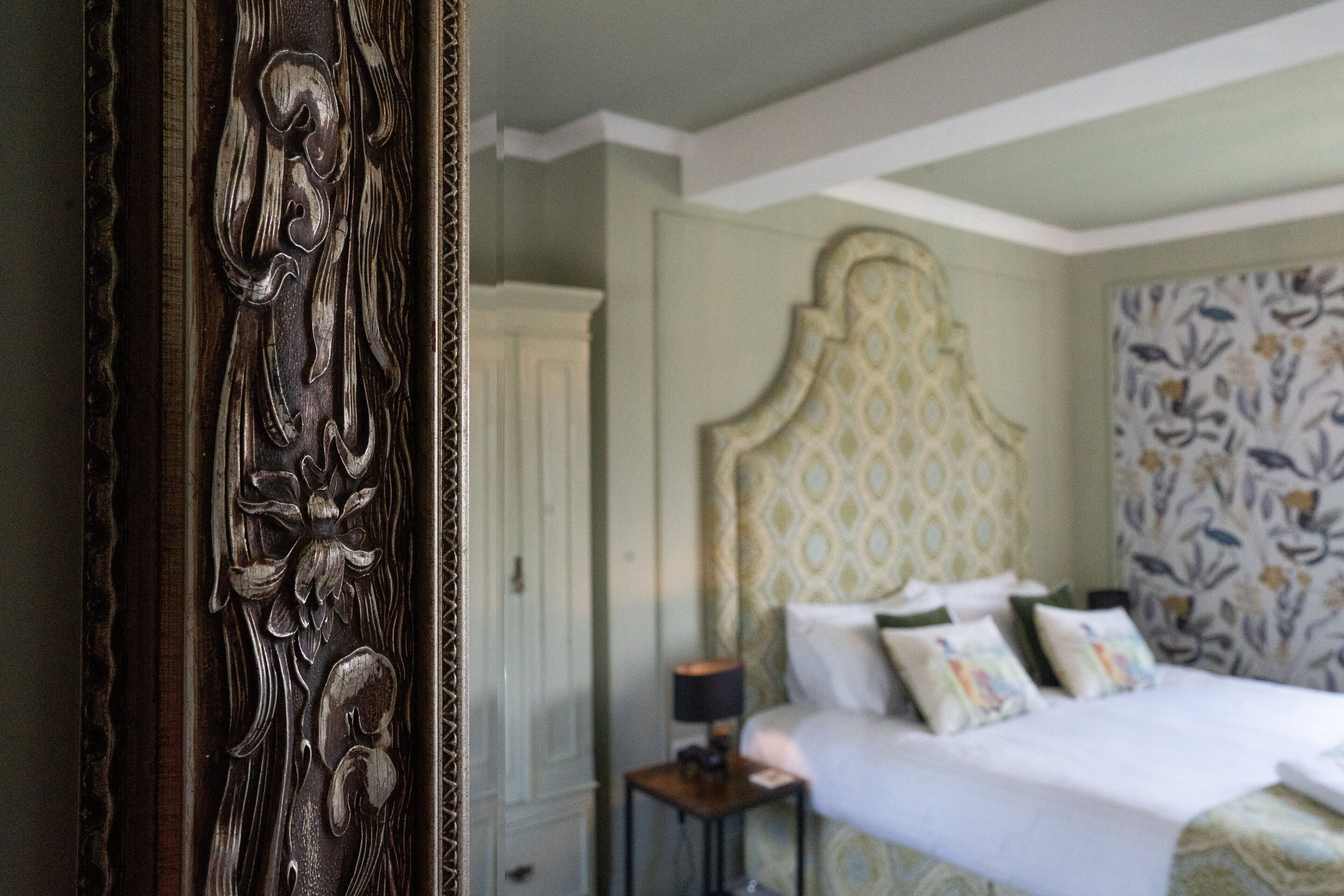 Un dormitorio con cama, mesita de noche y cabecero decorativo.