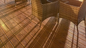 An outdoor seating area with wicker furniture and a table, overlooking a scenic landscape. - Welbeck Manor and Golf  (Plymouth)