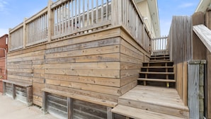 Une terrasse en bois dotée de bancs intégrés et d’un escalier menant à un balcon.