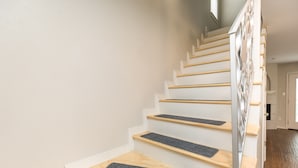Un escalier avec des marches en bois et une rampe, menant à une pièce dotée d’une porte et d’une fenêtre.