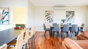 A modern dining area with a long table, multiple chairs, and a wooden floor. - 113 Barrage Rd Goolwa South (Goolwa South)