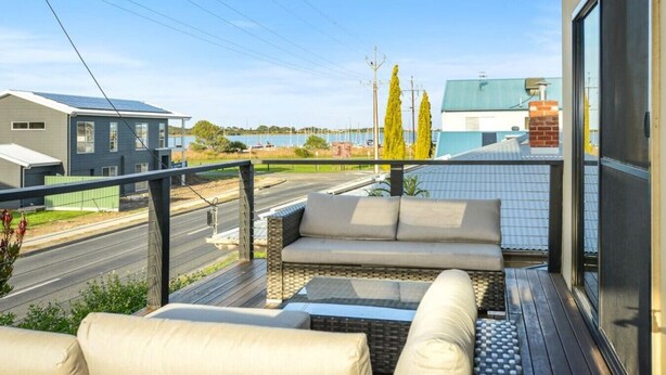 A balcony with outdoor seating, a view of a road, and buildings in the background. - 113 Barrage Rd Goolwa South (Goolwa South)