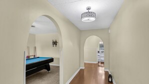 A hallway with a pool table, a ceiling light fixture, and an arched doorway. - 3Br, 2Ba, 6 beds, 5 min from Fort Novosel (Daleville)