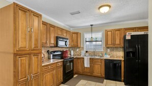 A kitchen with wooden cabinets, a black refrigerator, a microwave, a stove, and a dishwasher. - 3Br, 2Ba, 6 beds, 5 min from Fort Novosel (Daleville)