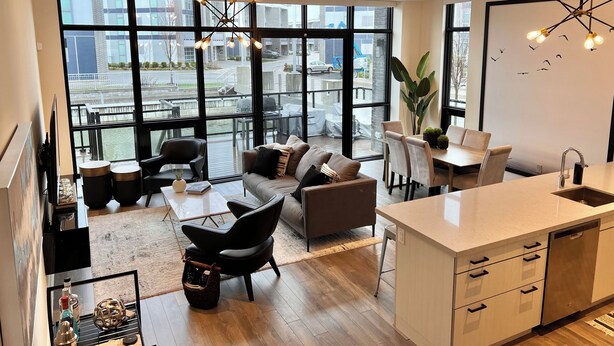 Eine moderne Wohnung mit Küche, Essbereich und Wohnzimmer. Sie verfügt über große Fenster, einen Balkon und Blick auf die Stadt.