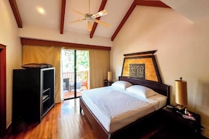 A bedroom with a bed, a ceiling fan, a nightstand, a lamp, and a sliding door to a balcony. - Beautiful 3-bed Villa in Cherngtalay, Thalang (Choeng Thale)