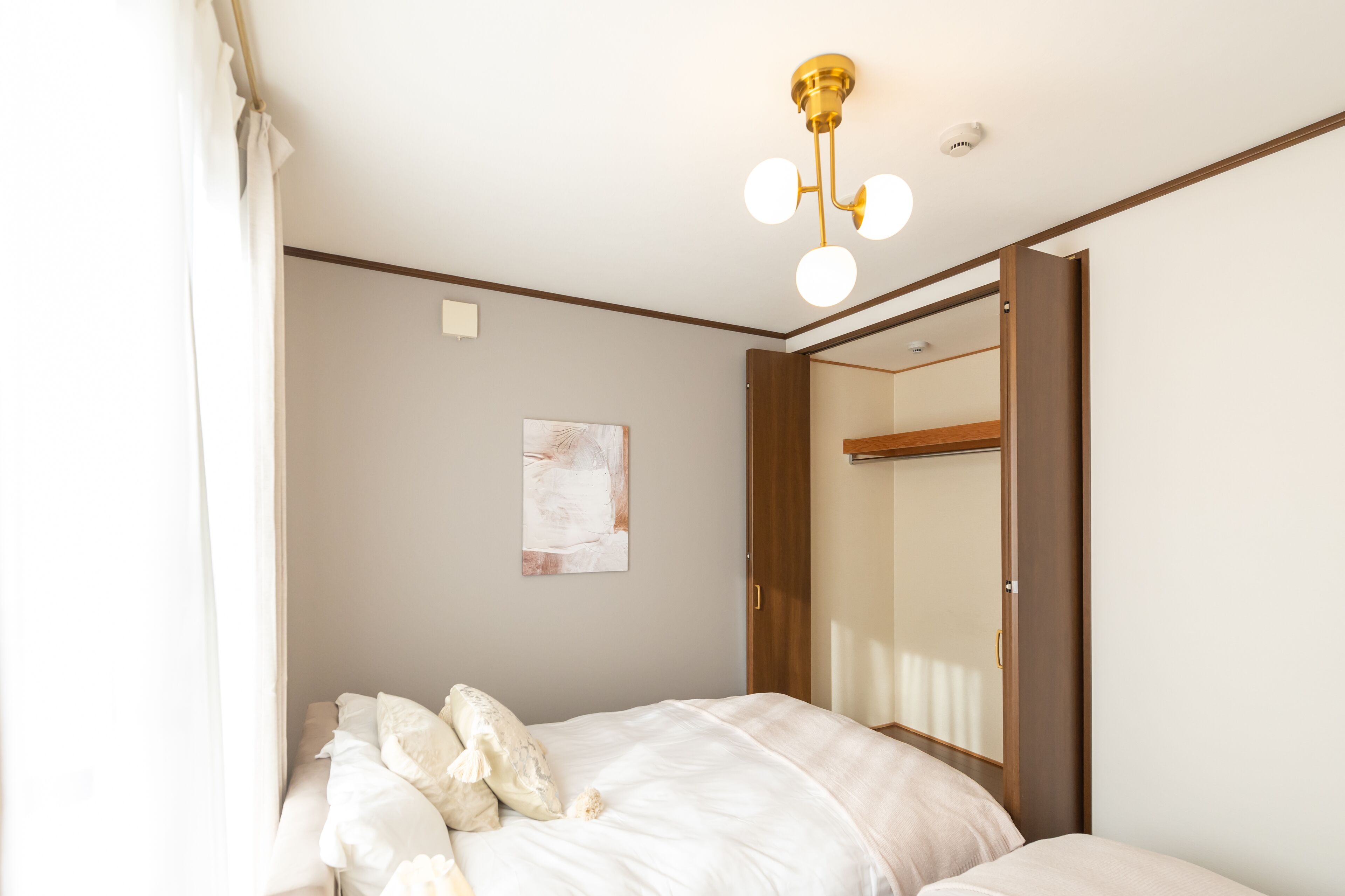 A bedroom with a bed, a mirror, a ceiling light fixture, and a wall-mounted artwork.